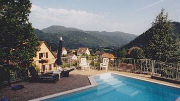Une piscine dotée de chaises longues et offrant une vue sur un village et des montagnes.
