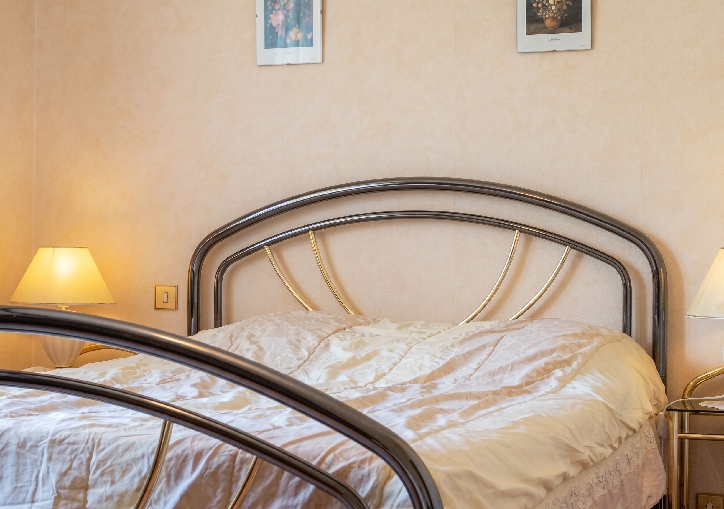 Un lit avec un cadre en métal, un couvre-lit blanc et deux lampes de chevet.