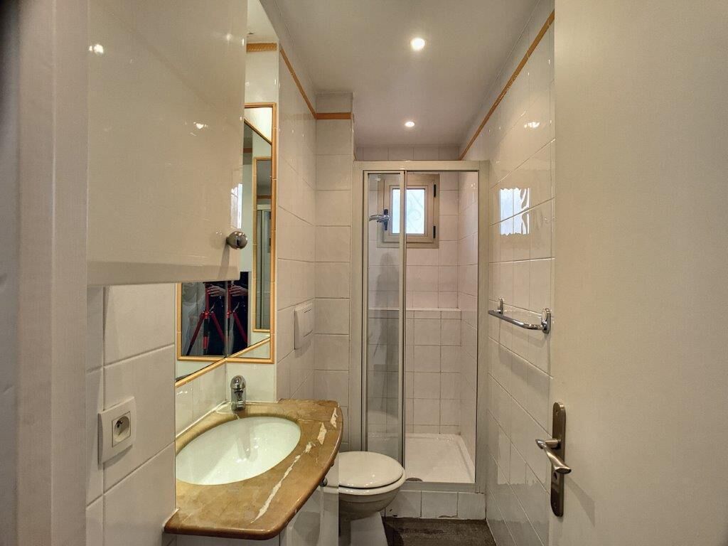 A small bathroom with a sink, toilet, and glass shower enclosure.