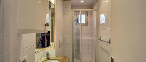 A small bathroom with a sink, toilet, and glass shower enclosure.