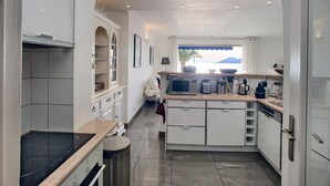 A modern kitchen with white cabinetry, a built-in microwave, and a large window with a view of the mountains. - 4 bedrooms - Close to palace - Sea front - Beaches on foot  . Near  Old Port (Cannes)