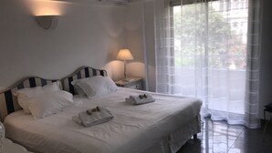 A hotel room with a large bed, a bedside table with a lamp, and a window with sheer curtains. - 4 bedrooms - Close to palace - Sea front - Beaches on foot  . Near  Old Port (Cannes)