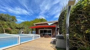 Um deck de madeira com piscina, área de estar externa e varanda coberta.