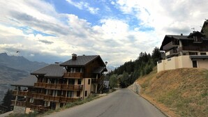 A mountain road leading to a chalet-style building with multiple balconies and a steep driveway. - 3-room apartment in Vallandry, southwest terrace, pets allowed (Peisey-Vallandry)
