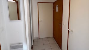 A narrow hallway with a tiled floor, a door with a wooden frame, and a small window with a mirror. - 3-room apartment in Vallandry, southwest terrace, pets allowed (Peisey-Vallandry)