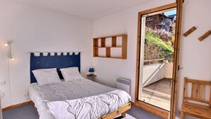 A bedroom with a bed, a nightstand, a wall-mounted shelf, and a window with a view of the outdoors. - 3-room apartment in Vallandry, southwest terrace, pets allowed (Peisey-Vallandry)