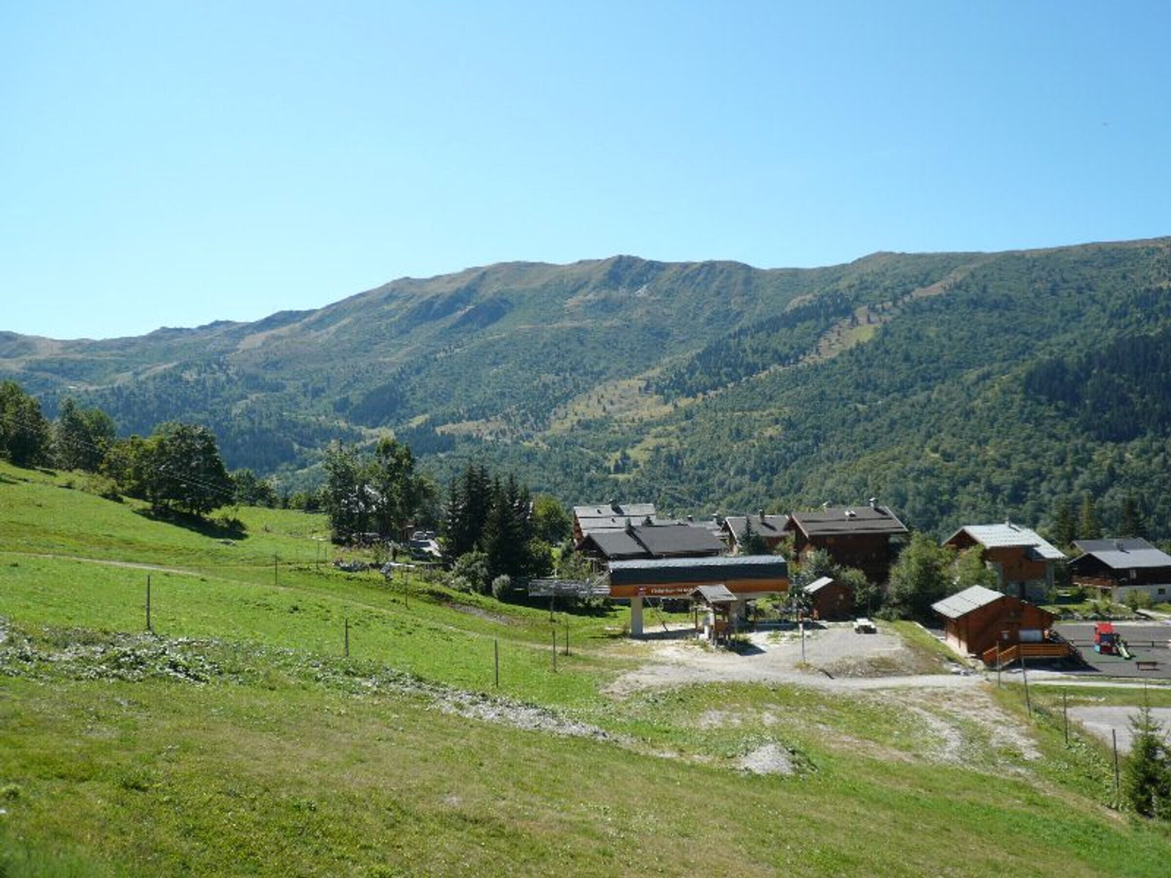 A rural village with traditional wooden houses, a small road, and a mountain backdrop.