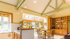 A spacious kitchen with a dining area, large windows, and a built-in bookshelf. - Charming house with terrace in Normandy (Grosville)