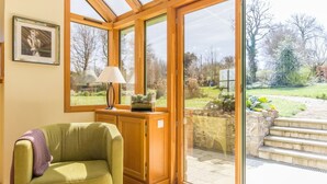 A cozy room with a green armchair, a lamp, and a large window overlooking a garden. - Charming house with terrace in Normandy (Grosville)