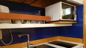 Een kleine keuken met een spoelbak, een magnetron en een vaatwasser.