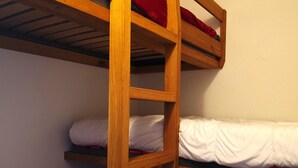 A bunk bed with wooden frames and white bedding.