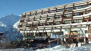 A multi-story hotel with a ski resort backdrop, featuring a restaurant and a bar.