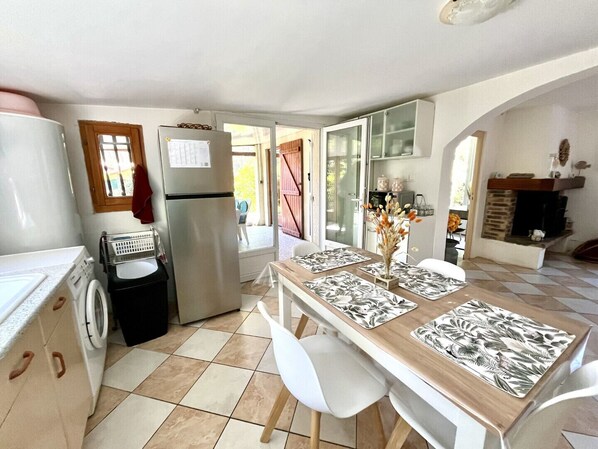 A compact kitchen with a washing machine, a refrigerator, and a dining area with a table set for two.