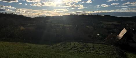 Paisaje rural con cielo despejado, luz solar y una vista distante de un pueblo.