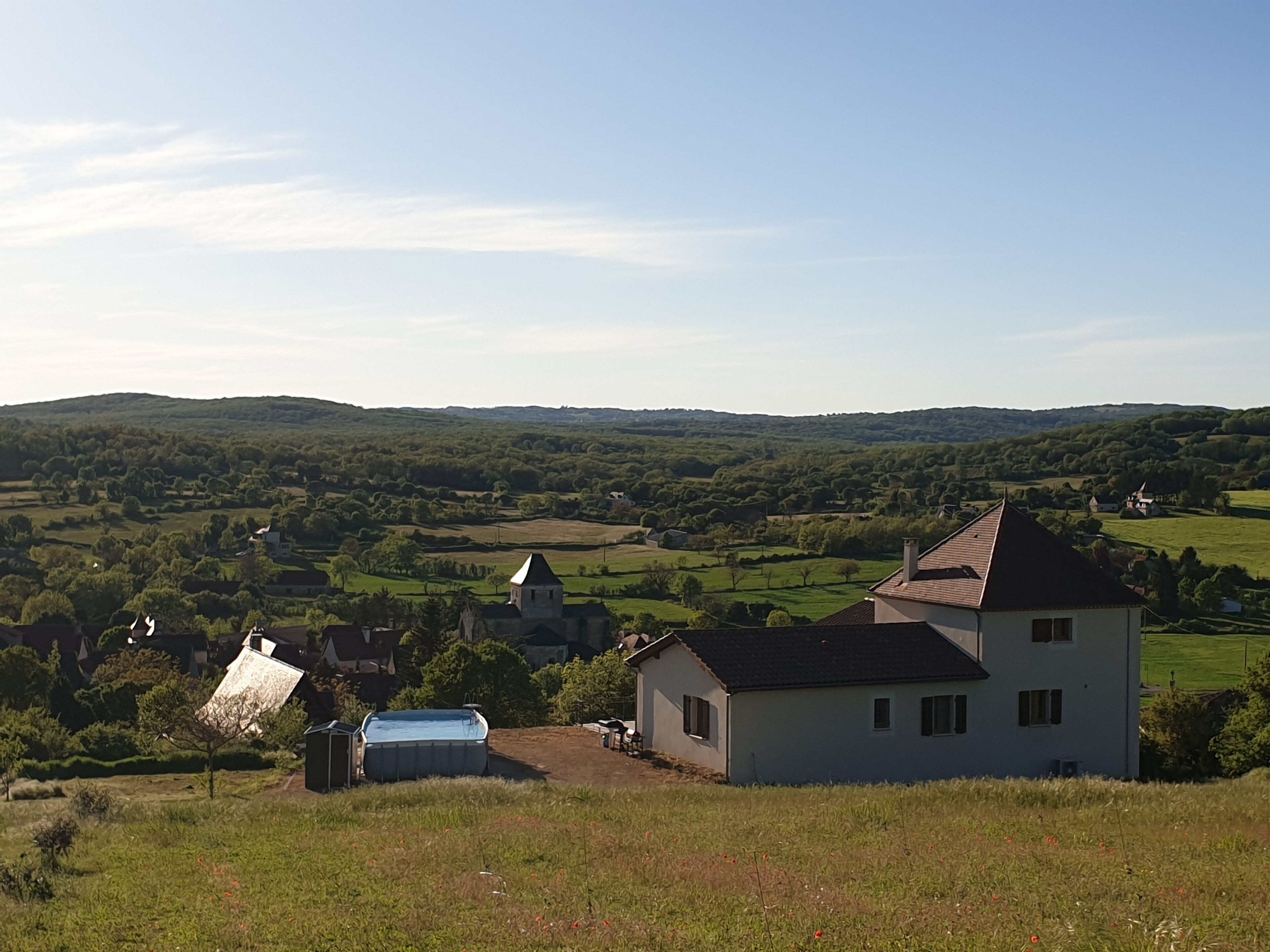 A rural landscape with a white house, a small building, and a church.