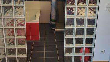 A modern bathroom with a bathtub, shower, and glass partition.
