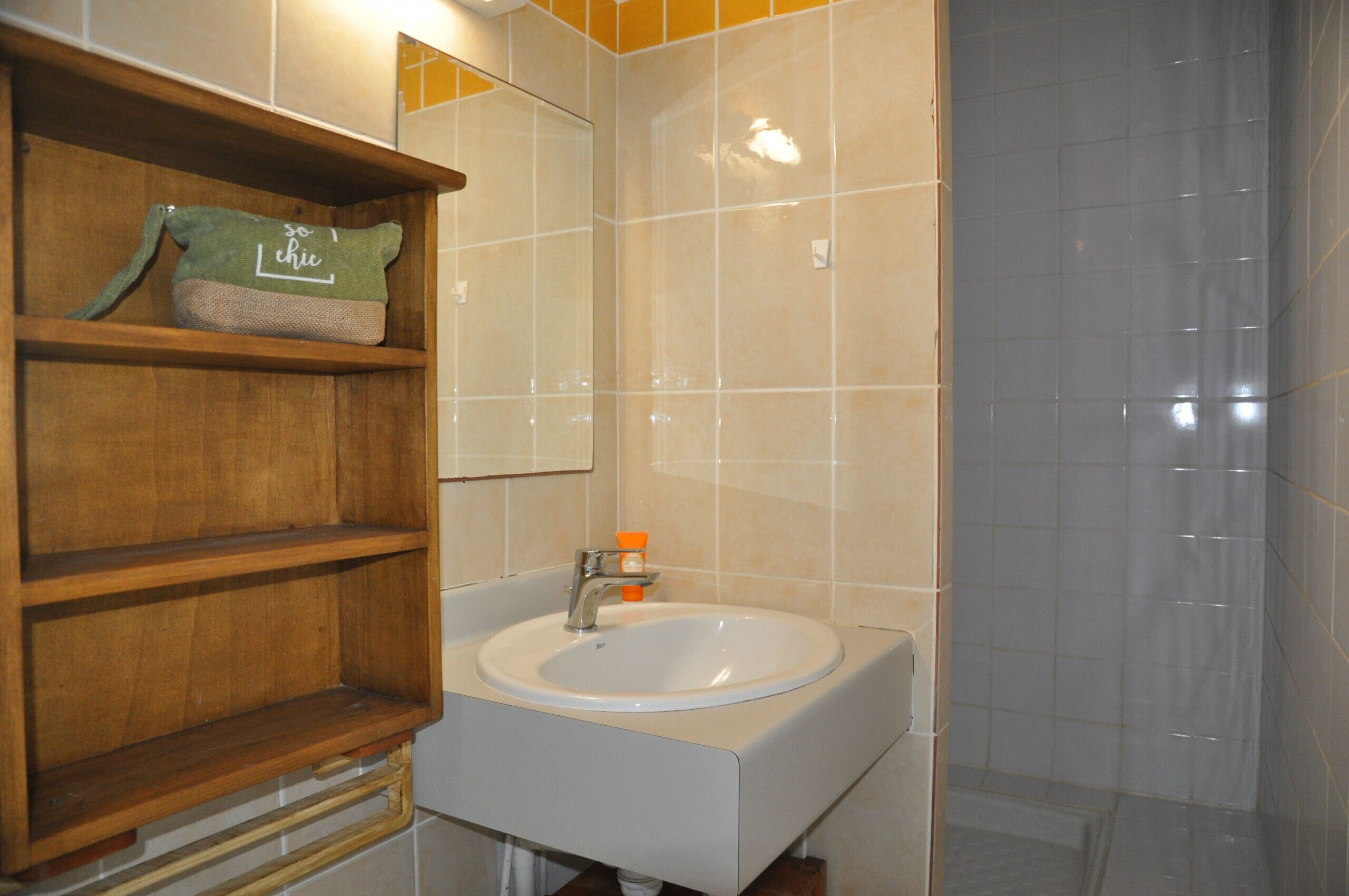 A bathroom with a white sink, wooden shelves, and a mirror.