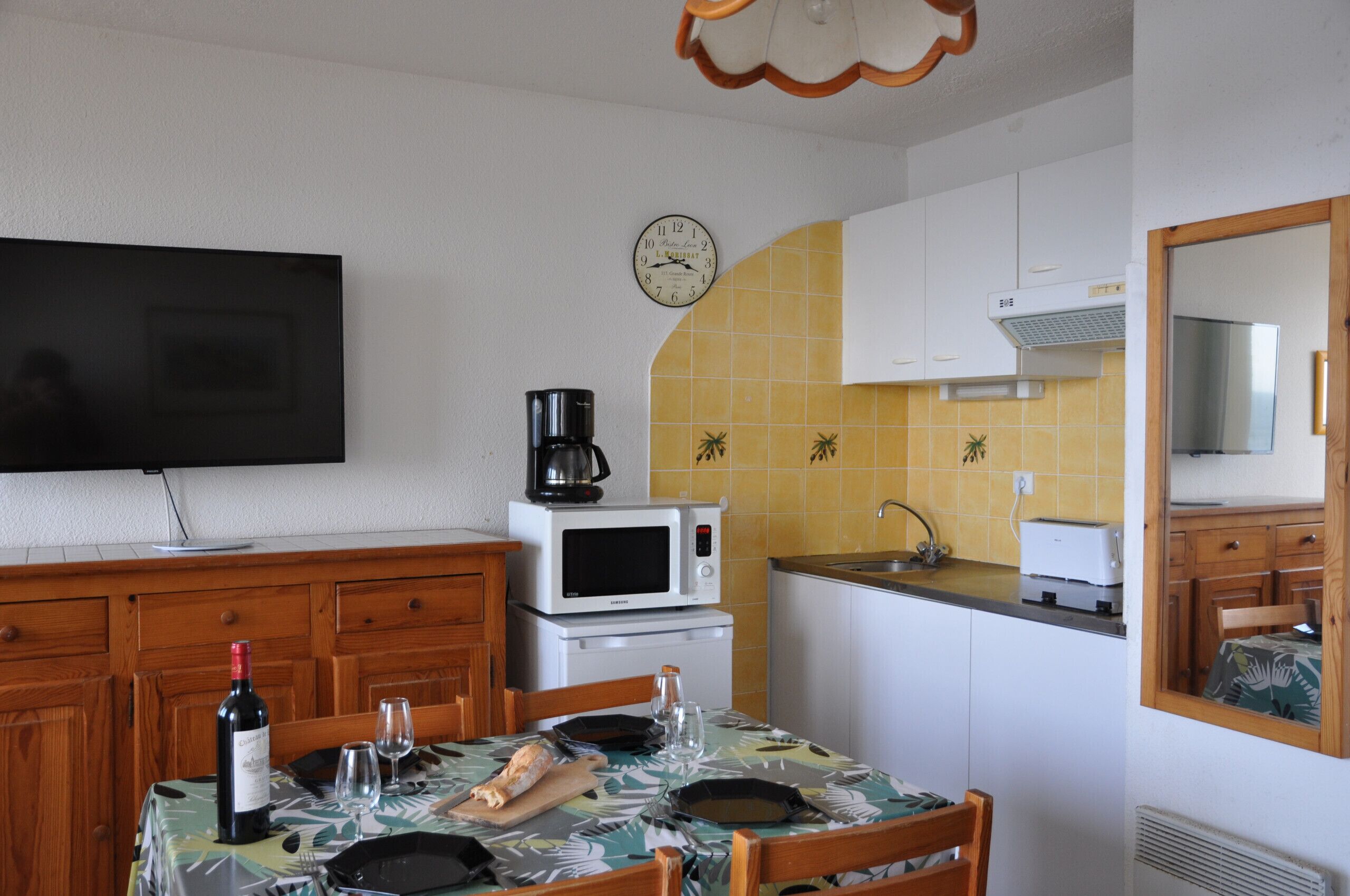 Une petite cuisine équipée d’un four à micro-ondes, d’une machine à café et d’une horloge murale.