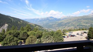 A mountainous landscape with a parking area and a view of distant hills.