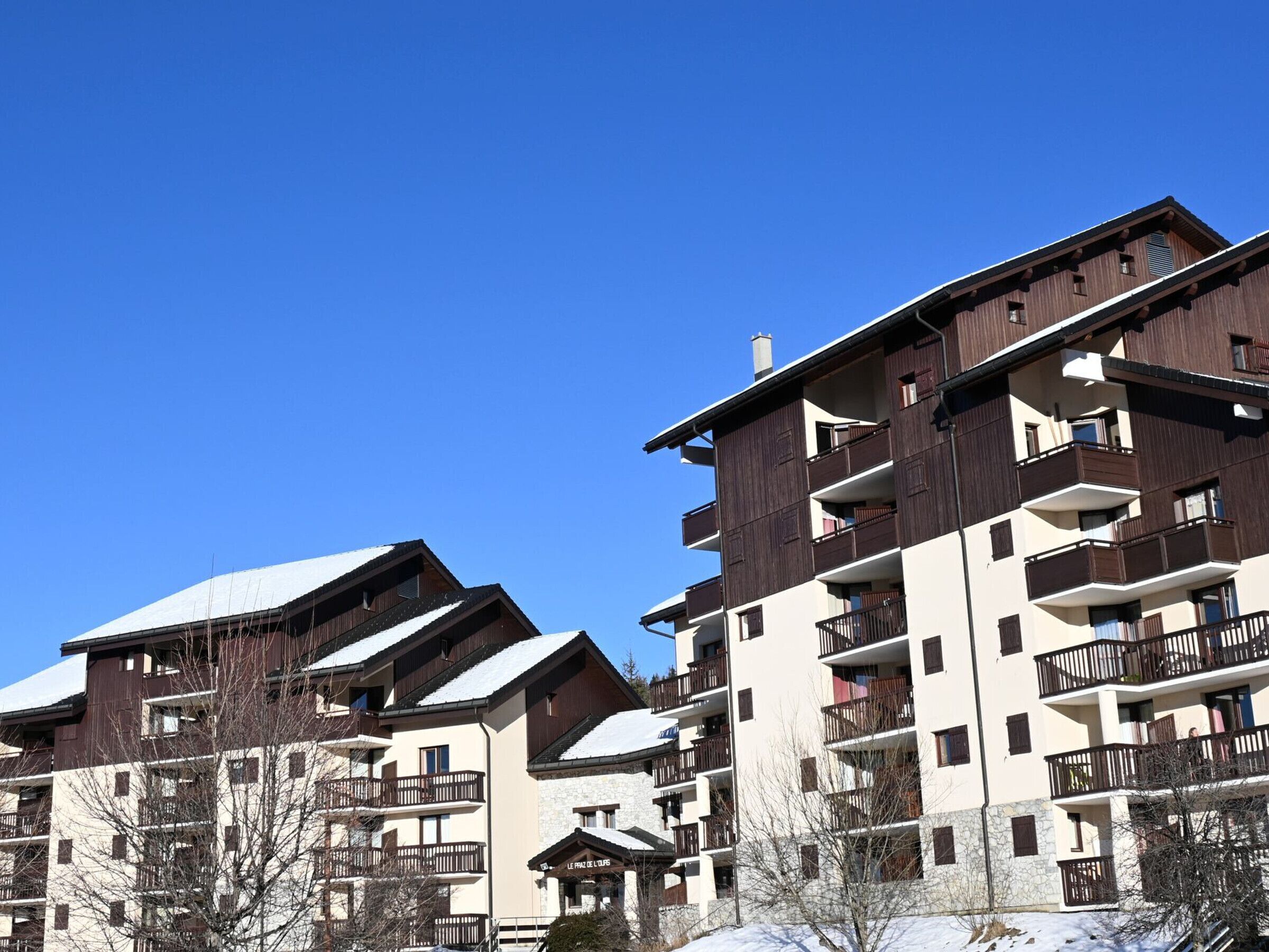 Un hôtel à plusieurs étages, doté de balcons et d’un toit enneigé.