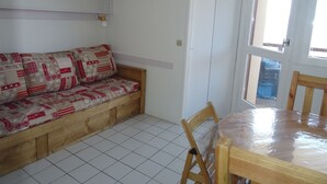 A cozy room with a wooden bench and a cushioned bench with a quilted cover. A wooden dining table with chairs is visible.
