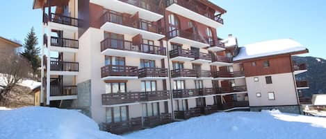A multi-story hotel with balconies, large windows, and a snowy landscape.