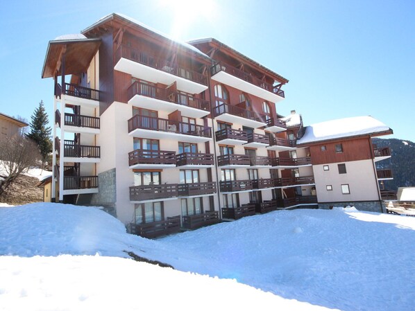 A multi-story hotel with balconies and a ski slope in the foreground.