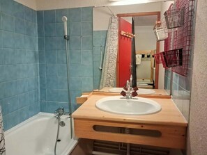 A bathroom with a bathtub, a shower, a sink with a wooden vanity, and a mirror.
