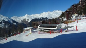 A snow-covered mountain slope with a modern ski lift and a building with a curved roof.