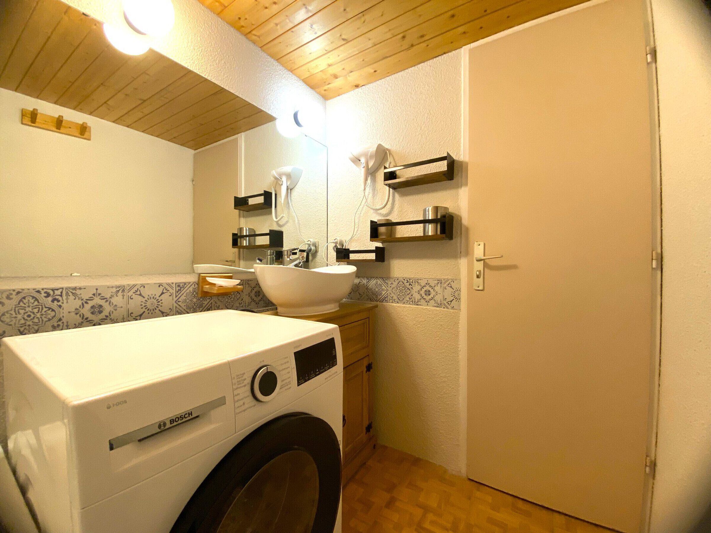 Un bagno funzionale con una lavatrice Bosch, un lavandino e uno specchio.