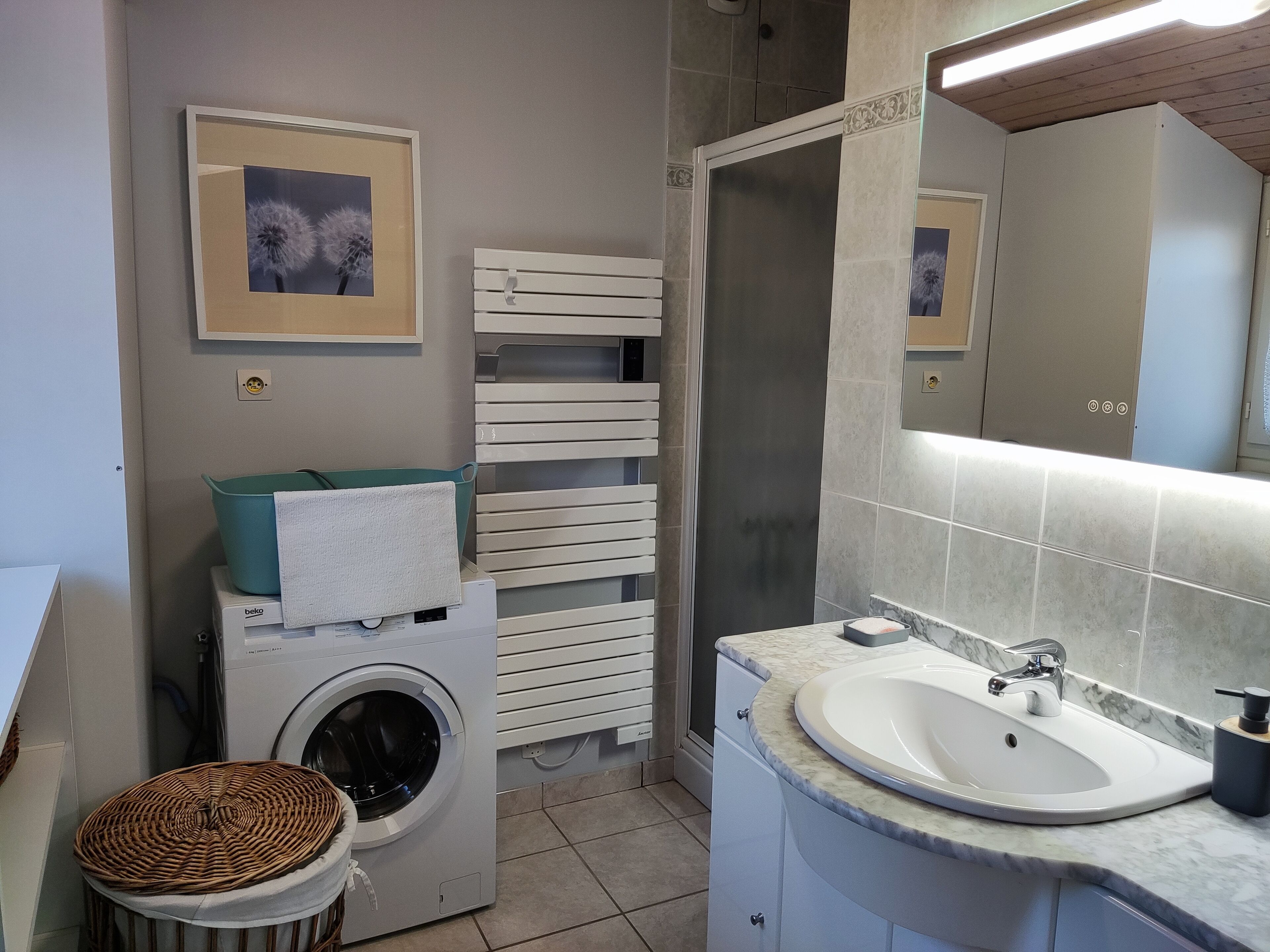 A compact bathroom with a washing machine, a sink, and a shower.