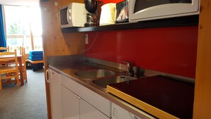 A compact kitchen with a microwave, coffee maker, and a sink. There is a wooden dining table and chairs in the adjacent area. - Large studio for 4 at Arc 1600 with wifi and pets allowed (Les Arcs 1600)