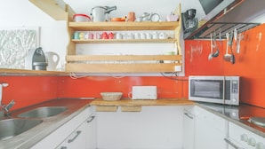 Une cuisine de taille réduite avec des meubles blancs, un plan de travail en bois, un four à micro-ondes et divers ustensiles de cuisine.