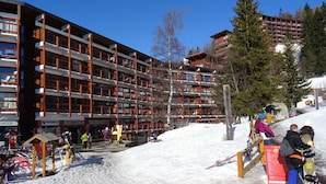 Un hôtel à plusieurs étages, avec une station de ski en arrière-plan.