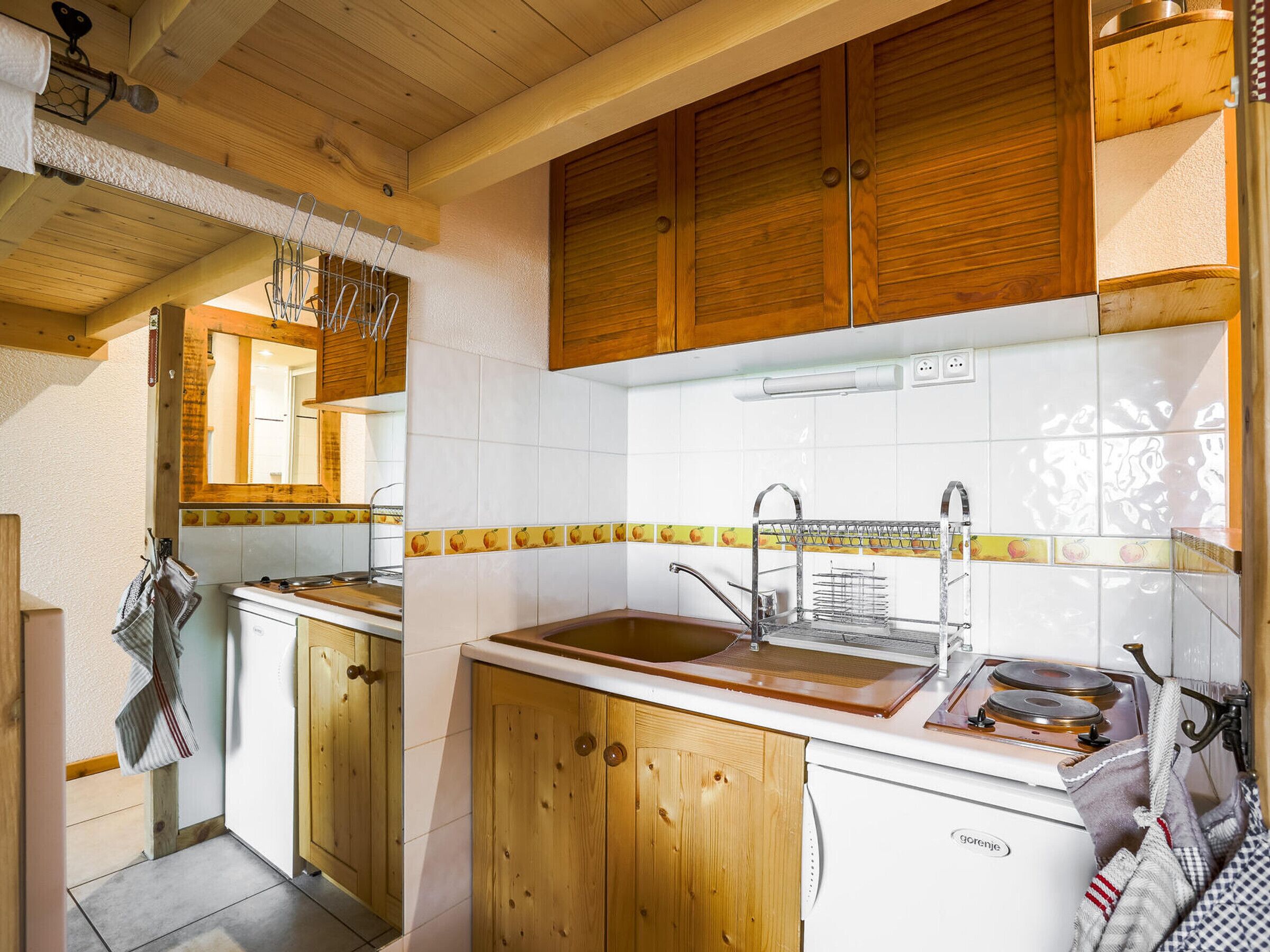 Une cuisine avec des meubles de rangement en bois, un plan de travail blanc, un évier et une cuisinière.