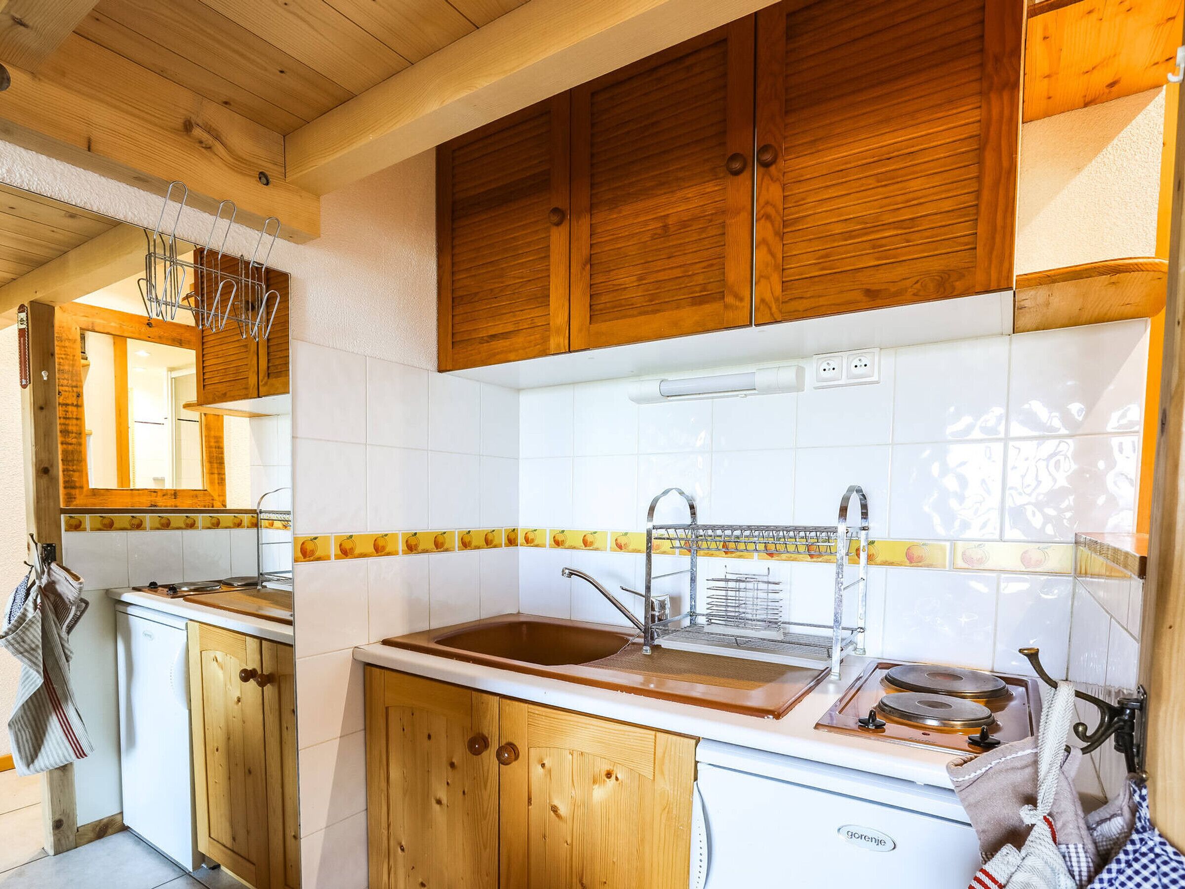 Una cocina con armarios de madera, encimera blanca y un lavamanos.