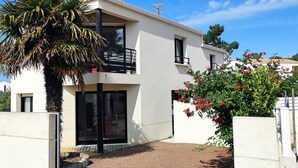 Un bâtiment moderne à deux étages, doté d’un balcon, de grandes fenêtres et d’une allée gravillonnée.
