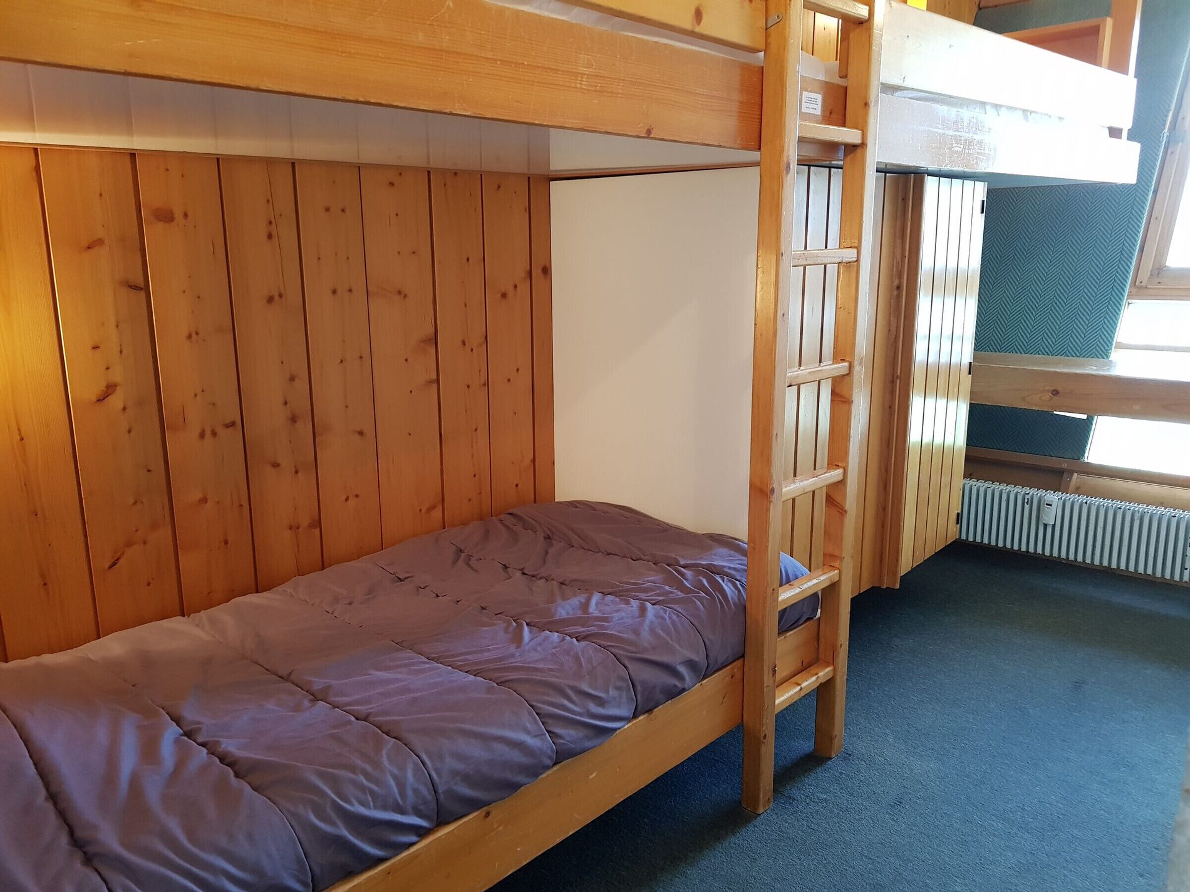 A bunk bed with a wooden headboard and a single bed below.