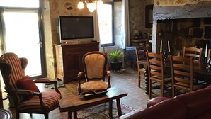 A cozy living room with a fireplace, a television, and a dining area with wooden furniture.
