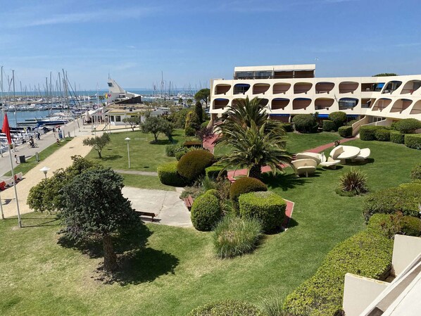 A marina with boats, a building with balconies, and well-maintained greenery. - 2-room apartment with pool and parking in Port Camargue (Port Camargue)