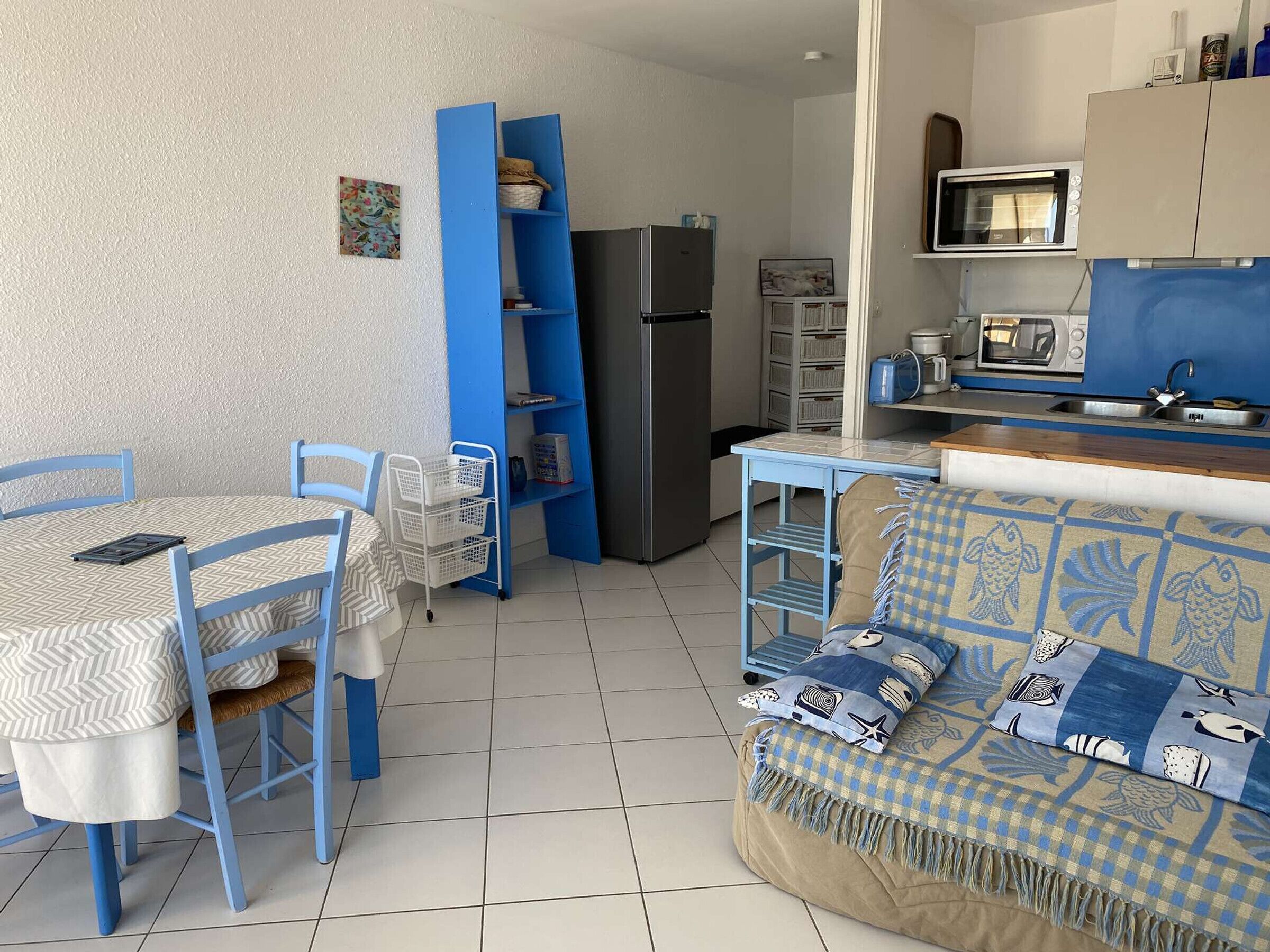 A compact living space with a dining area, kitchenette, and a sofa with patterned cushions.