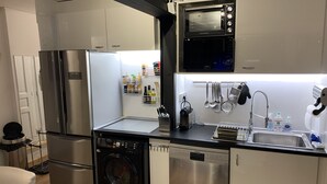 Una cucina funzionale con frigorifero in acciaio inox, forno integrato, lavatrice ed elettrodomestici inclusi.