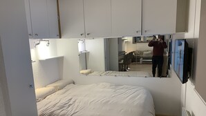 Una camera da letto con un letto, uno specchio grande e una televisione.