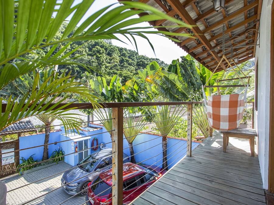 A wooden deck with a checkered umbrella, a blue wall, and parked cars.