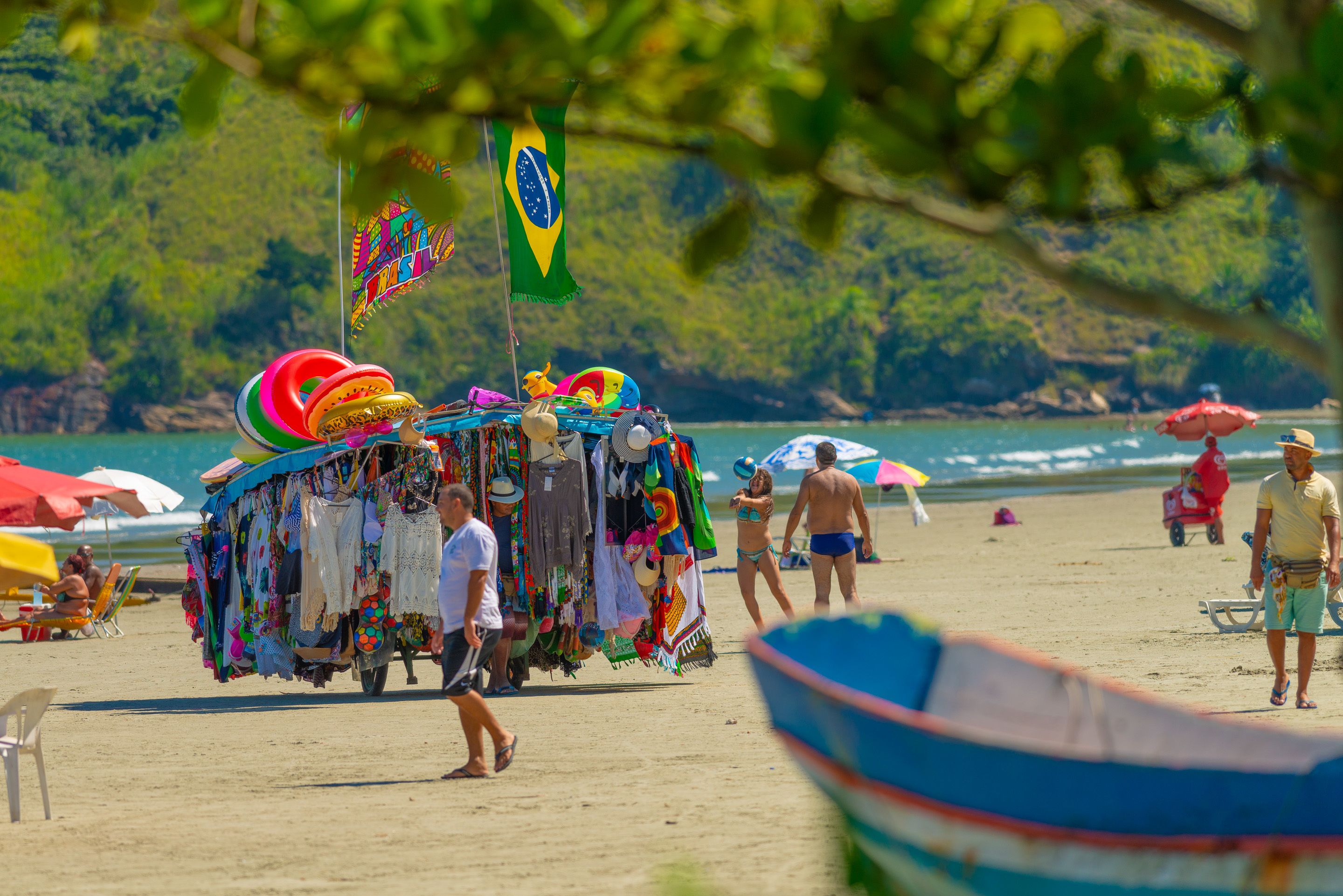Une plage avec un étal de marché aux couleurs vives et un drapeau.