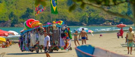 Une plage avec un étal de marché aux couleurs vives et un drapeau.