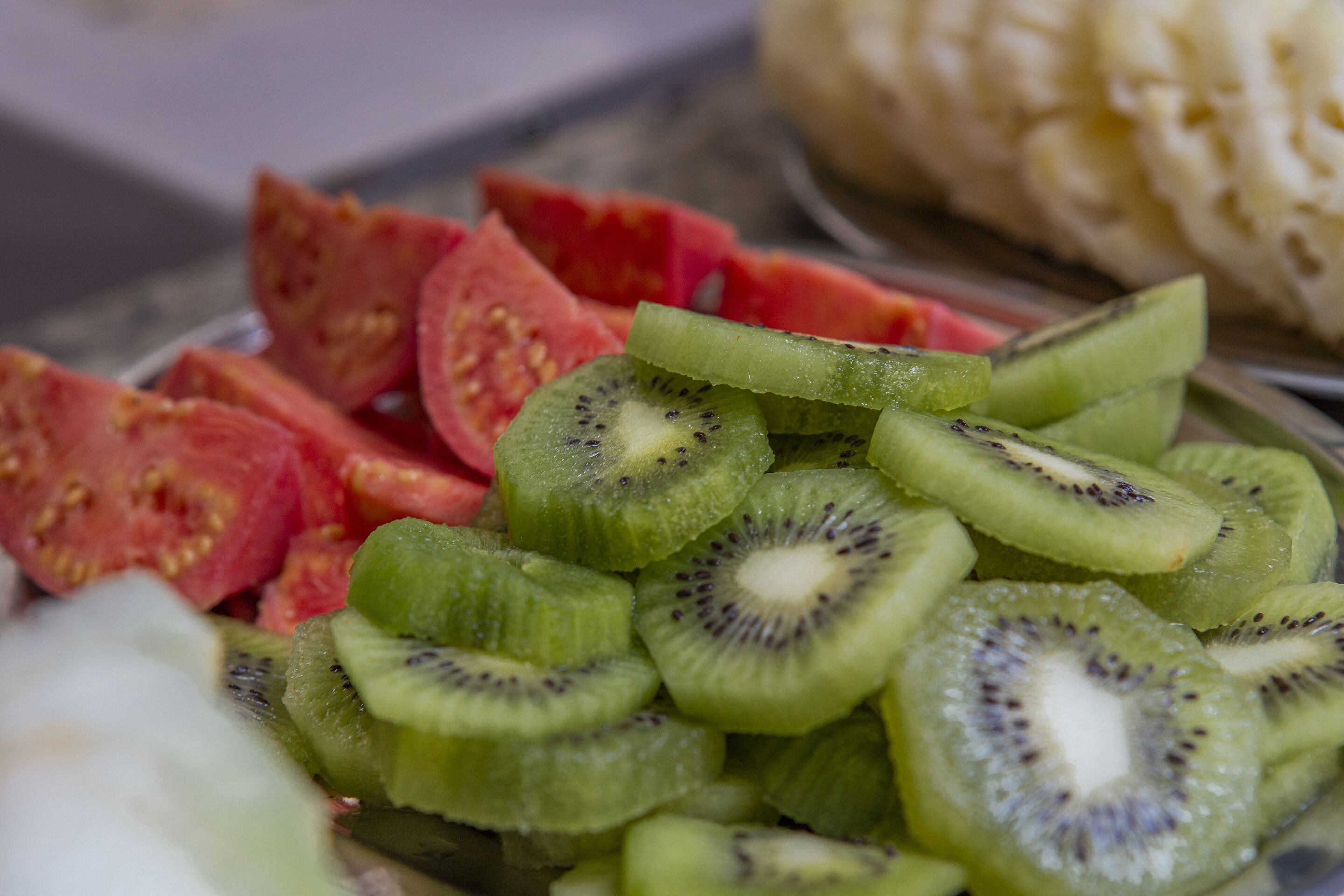 A plate of sliced fruits including kiwi and watermelon.