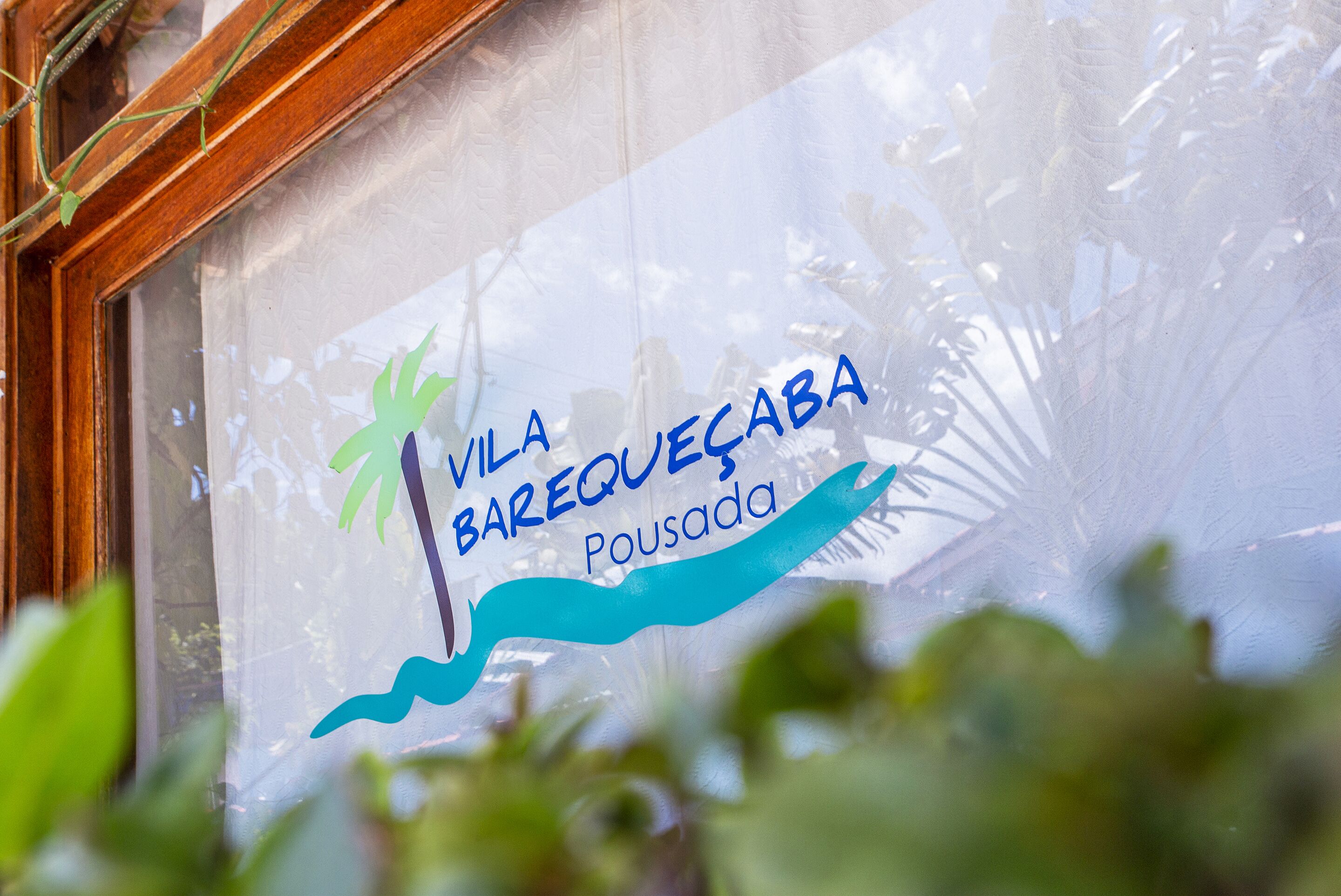 Una ventana con un letrero que dice "Vila Barequeçaba Pousada".