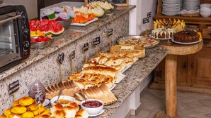 A buffet with various food items including bread, pastries, and fruits. - Pousada Vila Barequeçaba (São Sebastião)