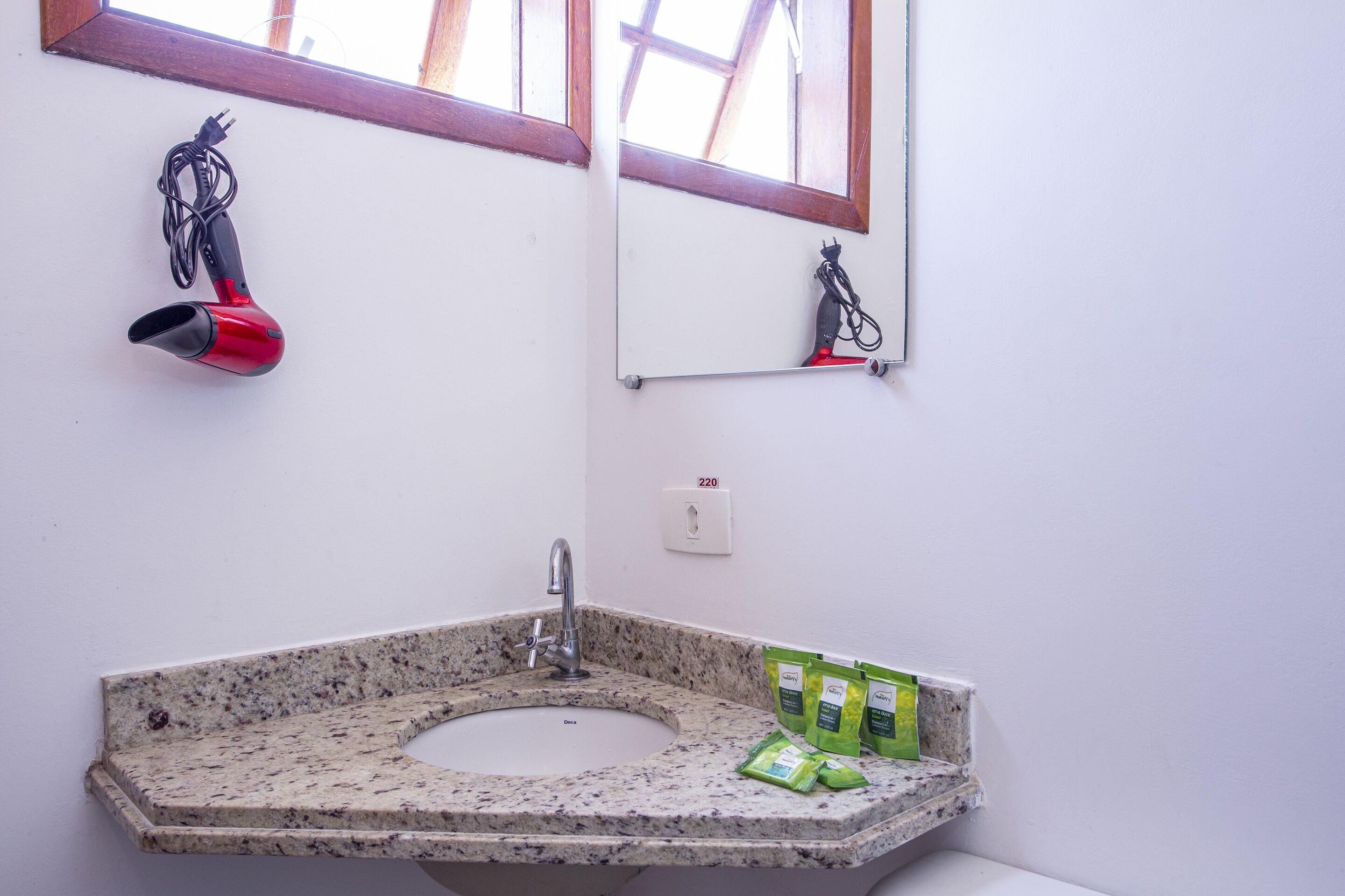 Un baño con un lavamanos de granito, un espejo y un secador de pelo colgado en la pared.